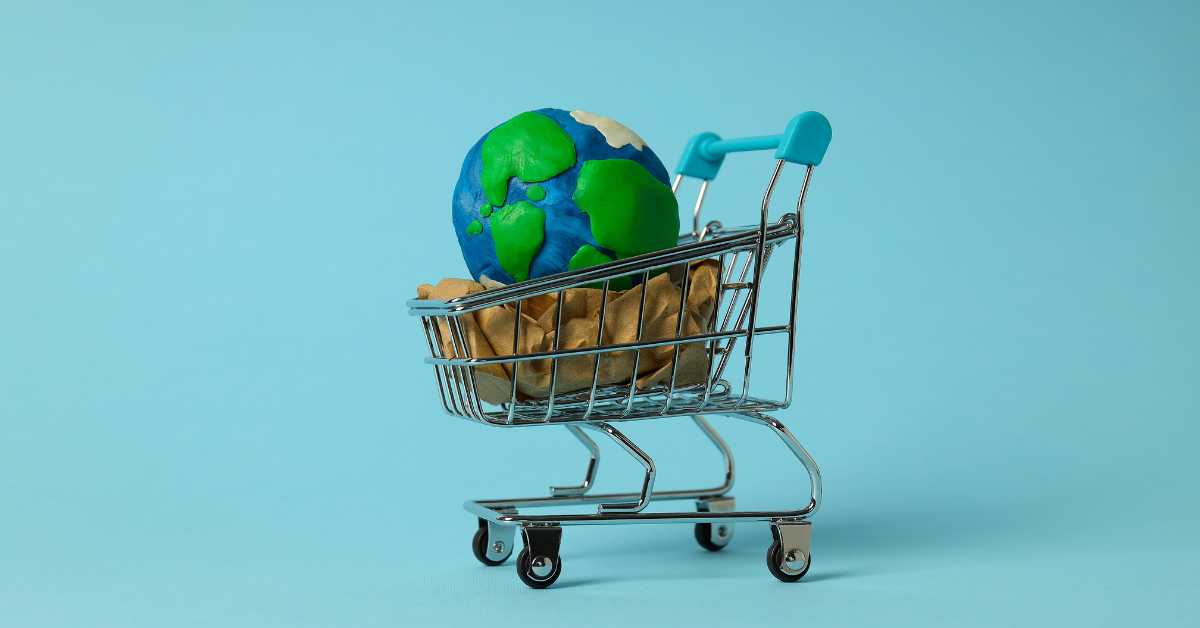 Das Bild zeigt einen Einkaufswagen mit einer Miniatur der Erde auf türkisem Hintergrund